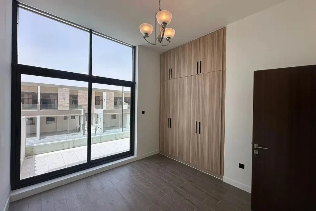 Unfurnished bedroom featuring built-in wooden wardrobe, floor-to-ceiling sliding glass window, and private terrace view at Elie Saab VIE at The Fields