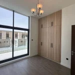 Unfurnished bedroom featuring built-in wooden wardrobe, floor-to-ceiling sliding glass window, and private terrace view at Elie Saab VIE at The Fields