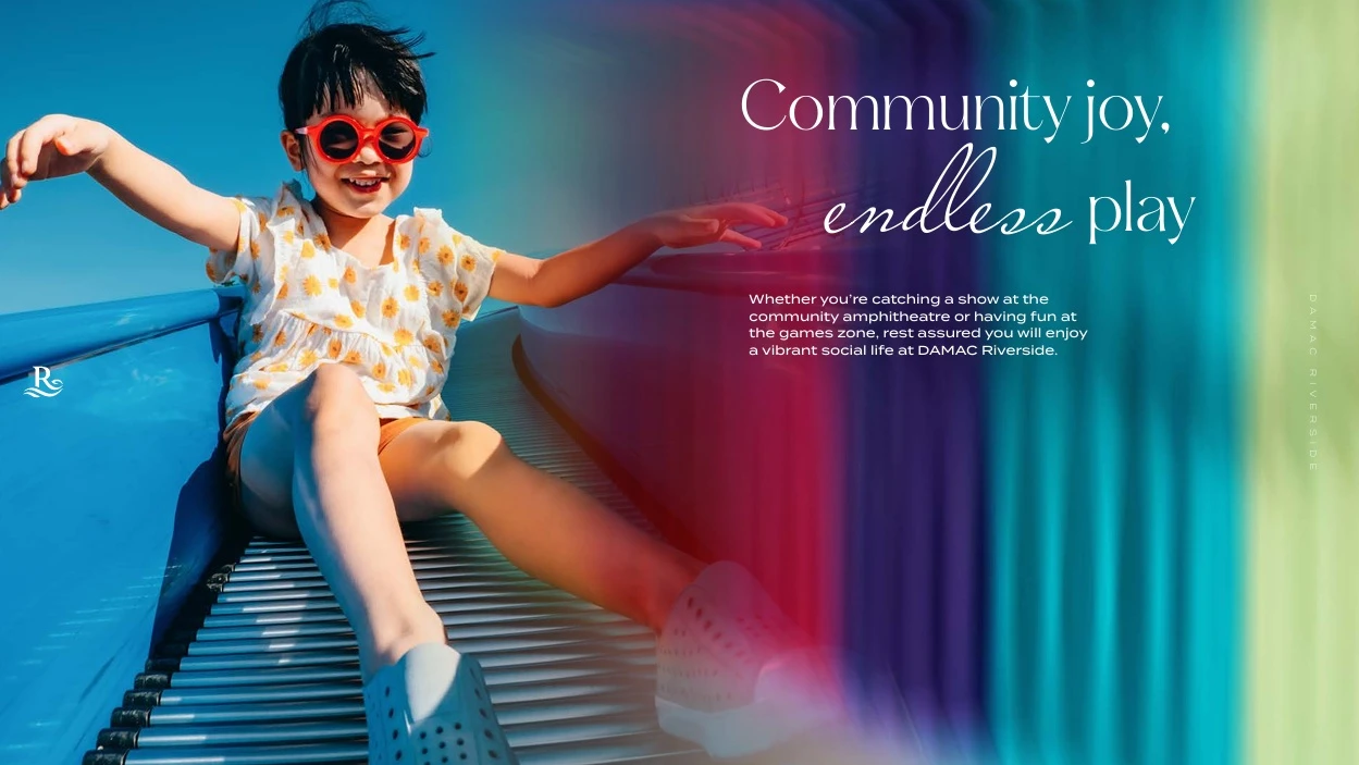 Young child sliding on a colorful playground slide in the kids play area and games zone at DAMAC Riverside Lush Dubai