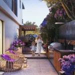 Private townhouse backyard with outdoor BBQ station, cozy seating, and floral landscaping at Violet 3 in DAMAC Hills 2