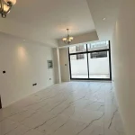 Large unfurnished living hall featuring white marble tiles, chandelier lights, and floor-to-ceiling glass window at Elie Saab VIE at The Fields