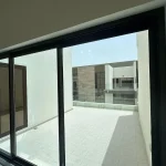 View of tiled outdoor terrace with glass railing through sliding glass doors at Elie Saab VIE at The Fields