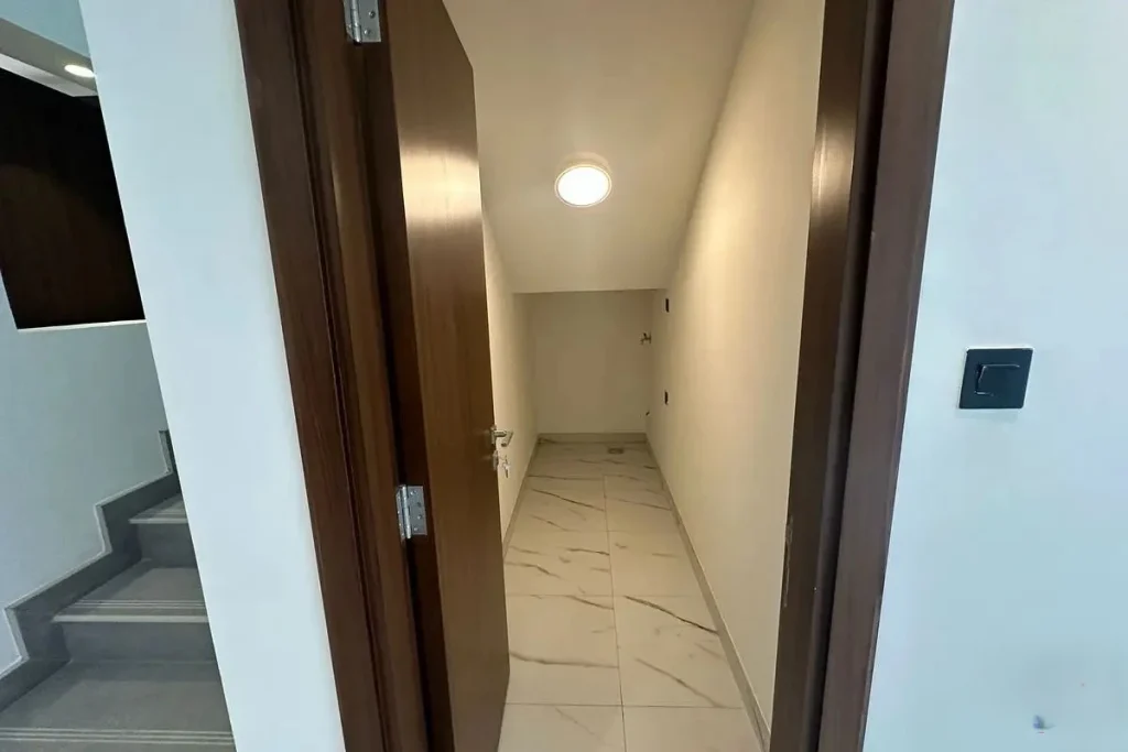 Interior view of a compact under-stair storage room with tiled floor and ceiling light at Elie Saab VIE at The Fields