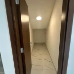 Interior view of a compact under-stair storage room with tiled floor and ceiling light at Elie Saab VIE at The Fields