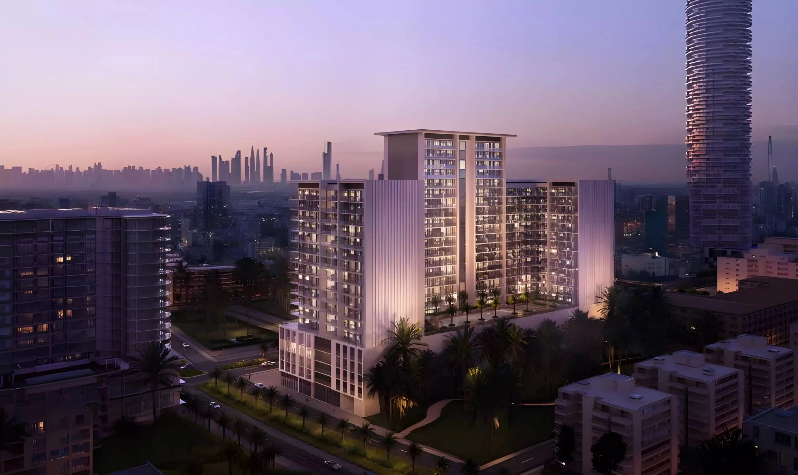 Aerial view of Binghatti Amberhall residential building in JVC Dubai illuminated at sunset with city skyline in background