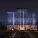 Illuminated night exterior facade of Binghatti Amberhall residential building in Jumeirah Village Circle Dubai