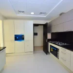 Fully fitted closed kitchen with black granite countertops, modern cabinetry, and built-in appliances at Grand Views in Meydan