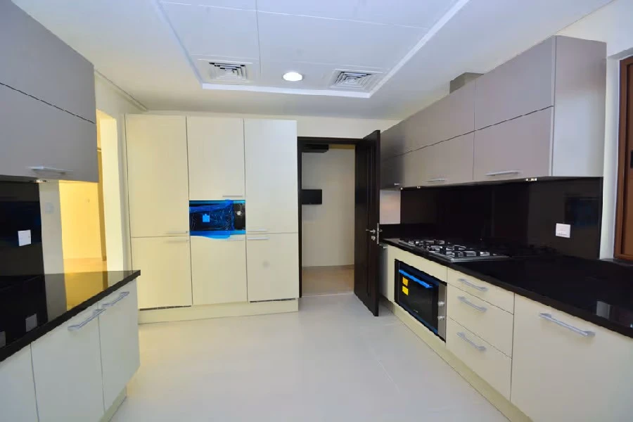 Fully fitted closed kitchen with black granite countertops, modern cabinetry, and built-in appliances at Grand Views in Meydan