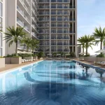 Outdoor swimming pool with sun loungers and palm trees at Binghatti Amberhall in Jumeirah Village Circle, Dubai