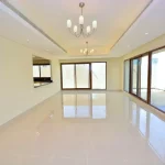 Large unfurnished living hall featuring modern chandeliers, polished tile flooring, and large glass sliding doors at Grand Views in Meydan
