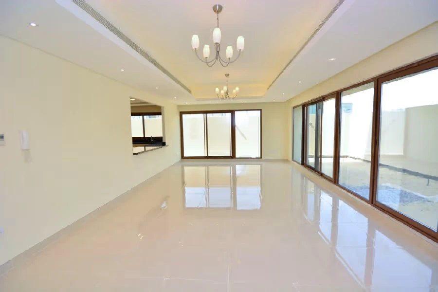 Large unfurnished living hall featuring modern chandeliers, polished tile flooring, and large glass sliding doors at Grand Views in Meydan
