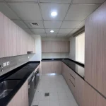 Spacious fitted kitchen with wooden cabinets and black countertop in a 4 bedroom townhouse at Senses at The Fields Dubai