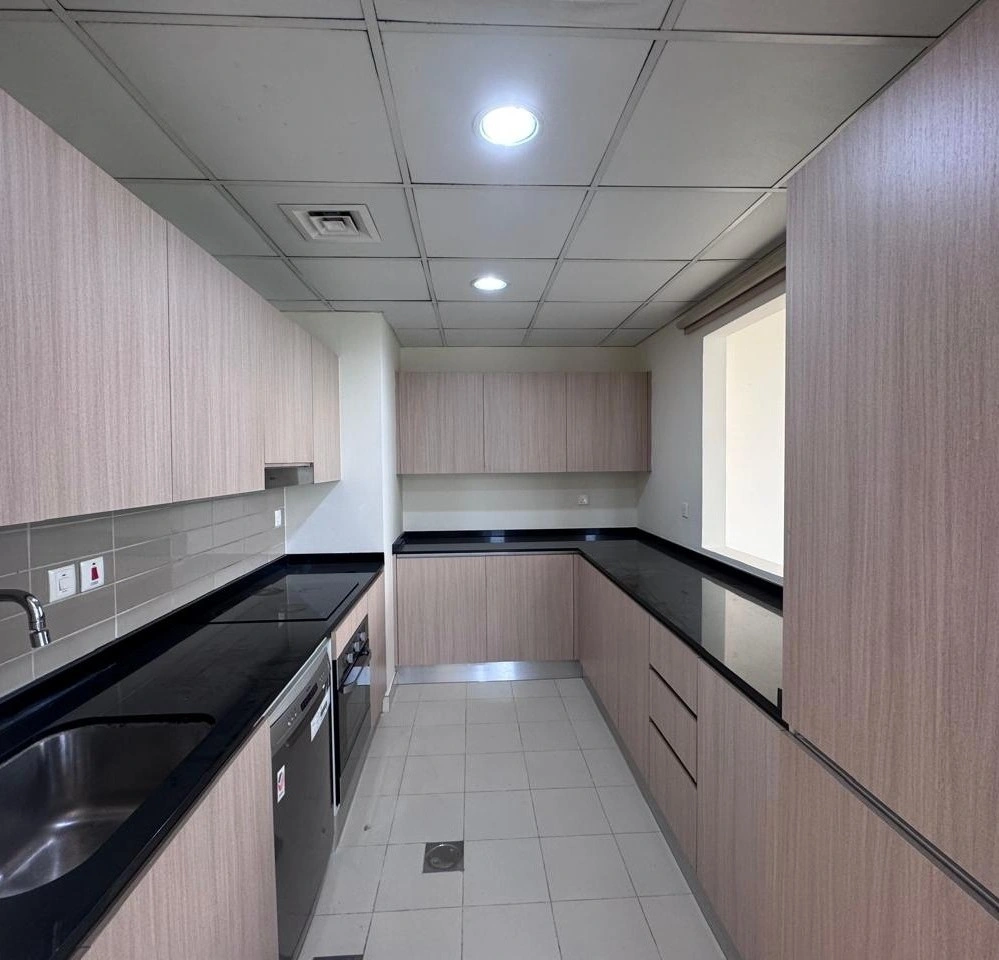 Spacious fitted kitchen with wooden cabinets and black countertop in a 4 bedroom townhouse at Senses at The Fields Dubai